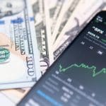 Afbeelding van mobiel op dollarbiljetten en de SP500 index