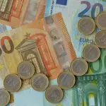 Een afbeelding met euro bankbiljetten en één euromunten die samen een stijgende pijl vormen