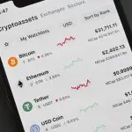 Een afbeelding van een telefoon met verschillende cryptocurrencies, waaronder bitcoin en ethereum