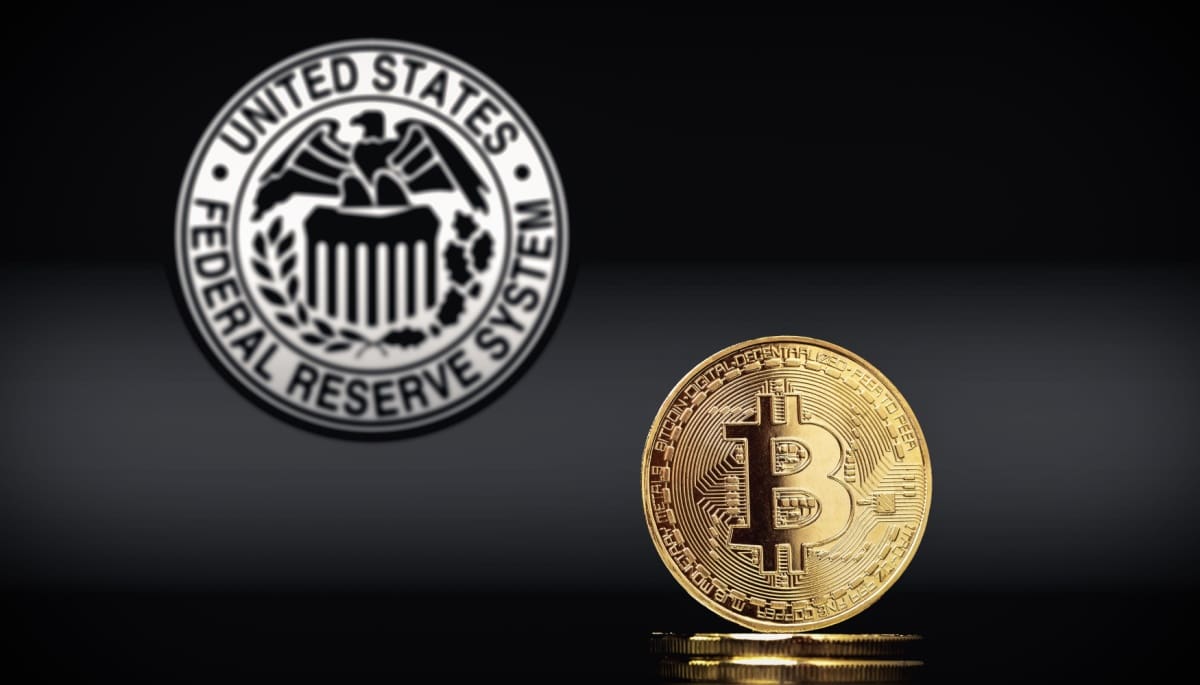 Een bitcoin munt in een zwarte afbeelding met op de achtergrond de Amerikaanse Federal Reserve