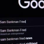 Een computer beeldscherm met de google zoekbalk, waar Sam Bankman-Fried (SBF) is ingevoerd, met verschillende zoeksuggesties