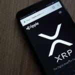 Foto van een mobiele telefoon met de website van Ripple geopend, met daarop het logo van XRP