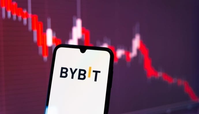 Het logo van cryptobeurs Bybit op een mobiele telefoon, met op de achtergrond een rode koers, representatief voor de koers van de gestolen ethereum (ETH)