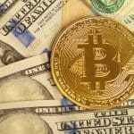 bitcoin op een stapel dollarbiljetten